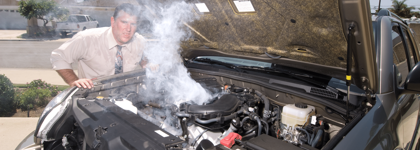 Man inspecting smoking car engine on a sunny day.