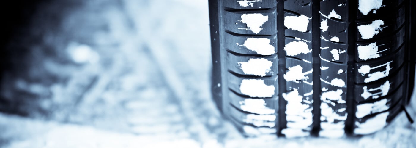 Close-up of a tire with snow-covered treads on a winter road.