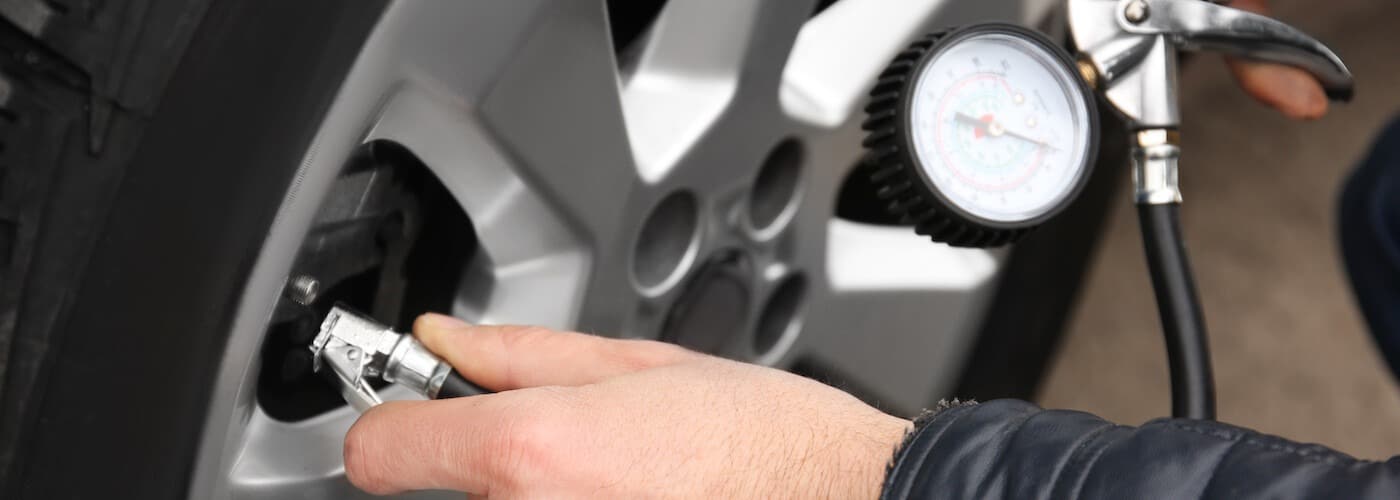 A person checks tire pressure with a gauge, ensuring proper car maintenance.