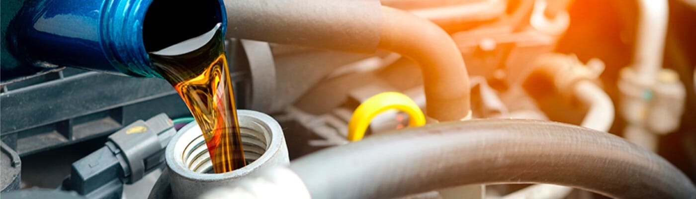 Pouring engine oil into a car engine with visible orange glow reflecting auto maintenance.