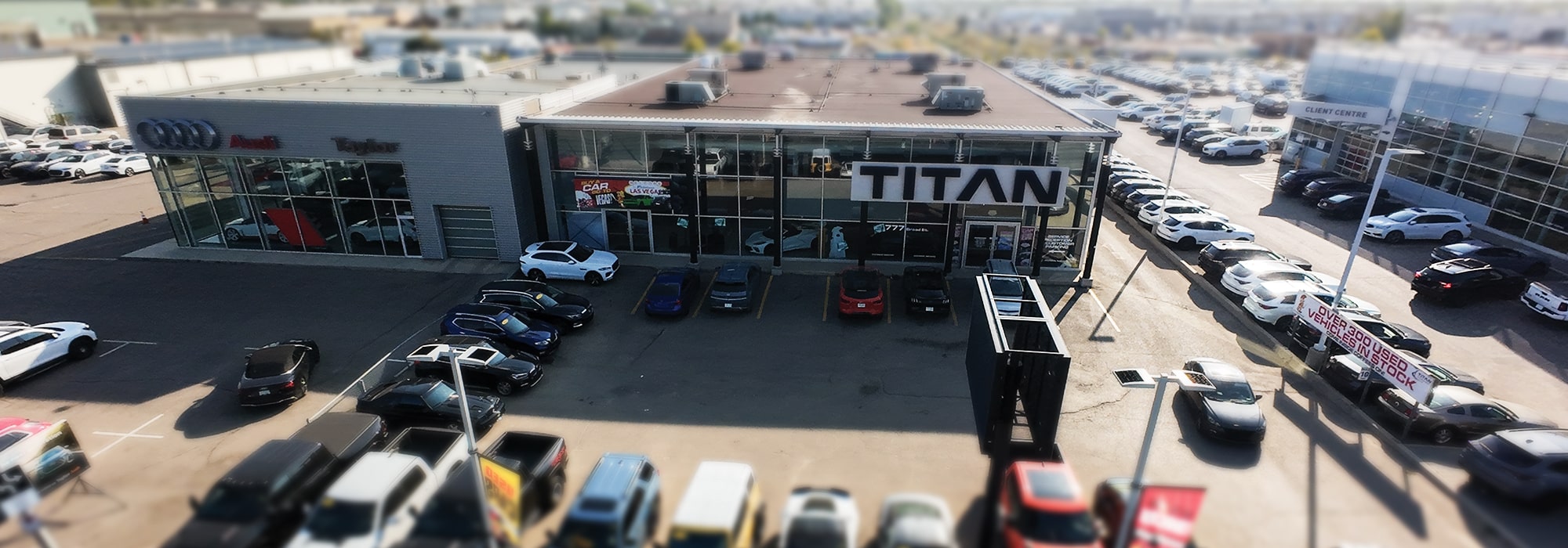 Showroom facade with illuminated "TITAN" sign, displaying vibrant sports cars inside.